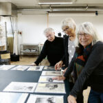   Lisa W Carlson, Kerstin Strandberg och Gunnel Oldenmark tittar på 
tidningsurklipp om KKV genom åren.