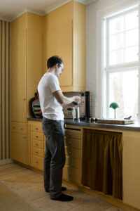 Alexander ställer iordning eftermiddagens kaffe i köket. Färger som leker med djärvt uttryck, skapar ett spännande lugn.