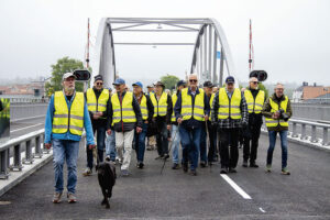 Umarellerna, som på plats följt hela bro- bygget, på väg över nya bron.